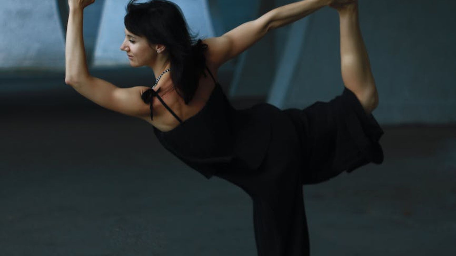 Silhouette of a woman in a calm yoga pose against a dark, serene background.